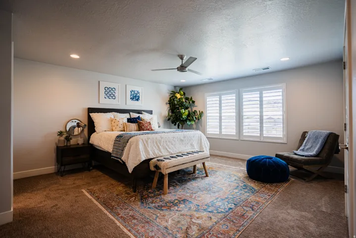 Recessed lighting, ceiling fan, two windows with plantation shutters, and carpeted flooring