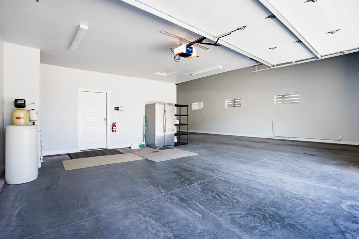 Spacious garage featuring a concrete floor, overhead lighting, and an automatic garage door opener