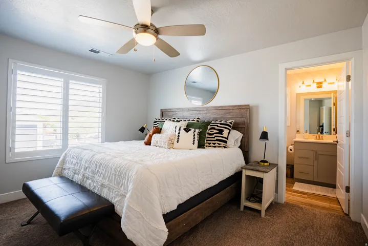 Room featuring a ceiling fan, window with white plantation shutters, and carpet flooring