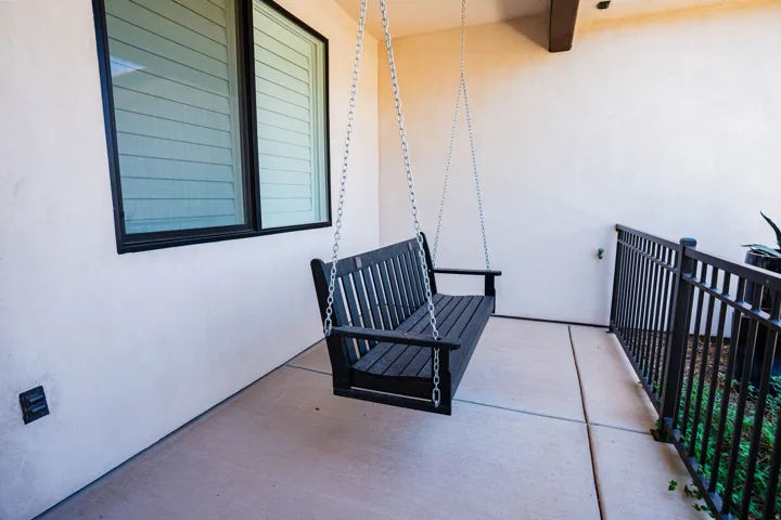 Patio featuring a concrete surface, a black metal railing, and a window with louvered blinds