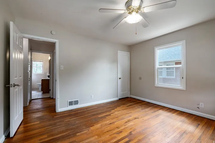 Hardwood flooring, neutral painted walls, ceiling fan, and a single window