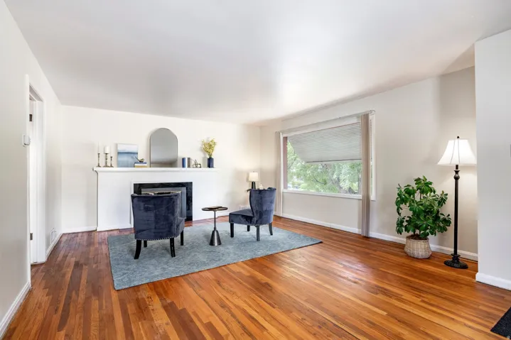 Hardwood flooring, white wall paint, white trim, white mantel, and a large window