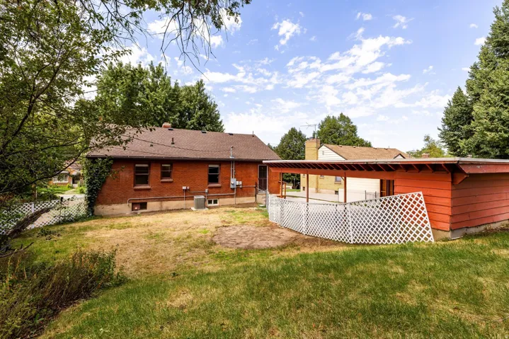 Brick exterior, covered patio, white lattice fencing, and mature trees