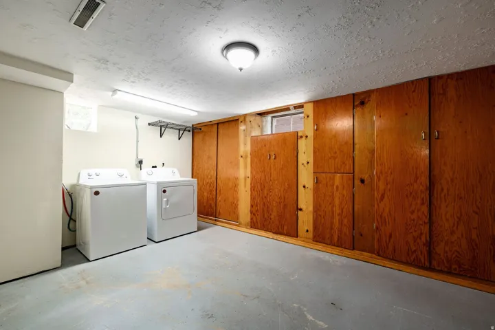 Built-in wood-finish cabinetry, painted concrete flooring, overhead flush mount lighting, and fluorescent lighting