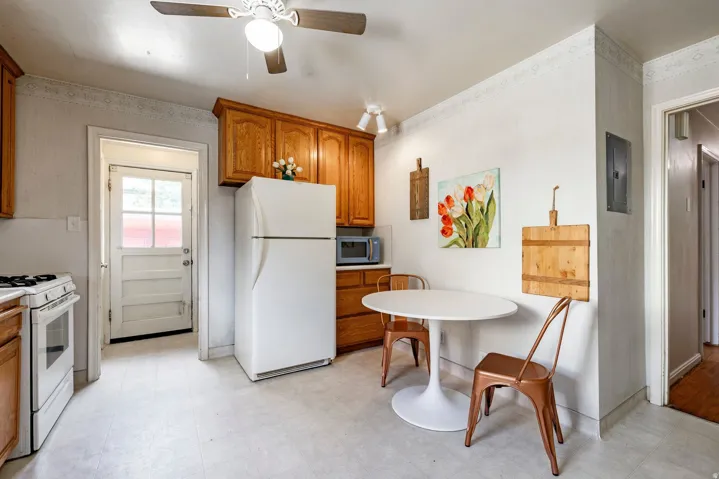 Kitchen featuring wood cabinetry, white appliances, and a ceiling fan