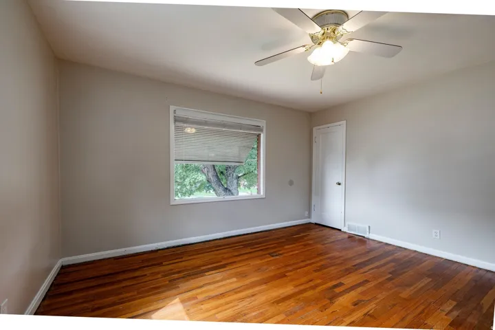 Hardwood flooring, painted walls, ceiling fan with light fixture, window with blinds, and white trim