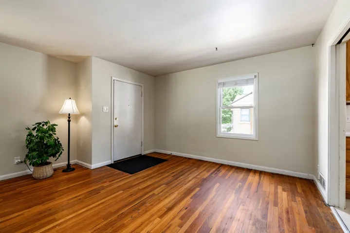 Hardwood flooring, painted walls, white trim, and a white window frame with natural light