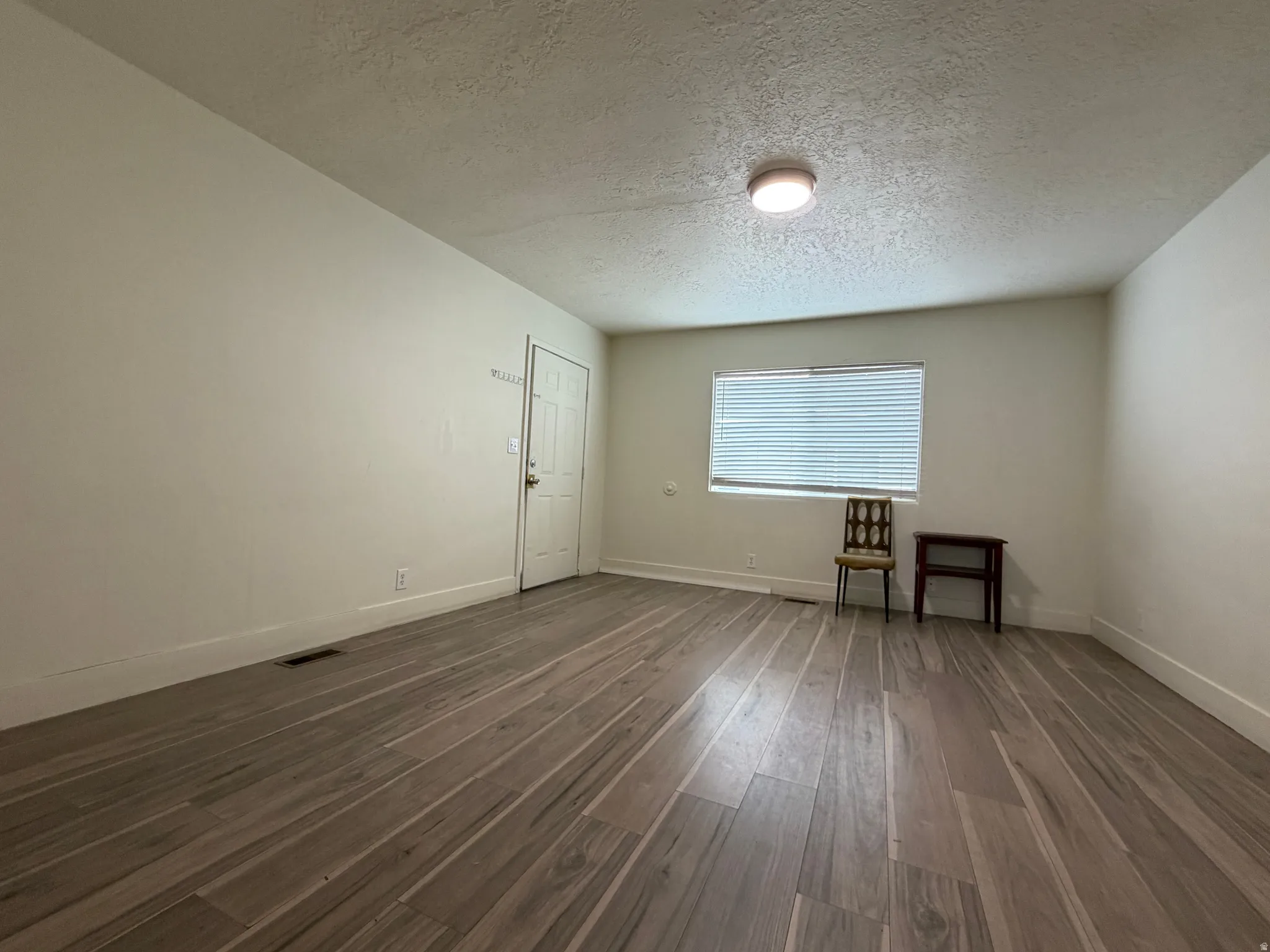 Wood-finish flooring, white walls, white trim, recessed lighting, and a single window with blinds