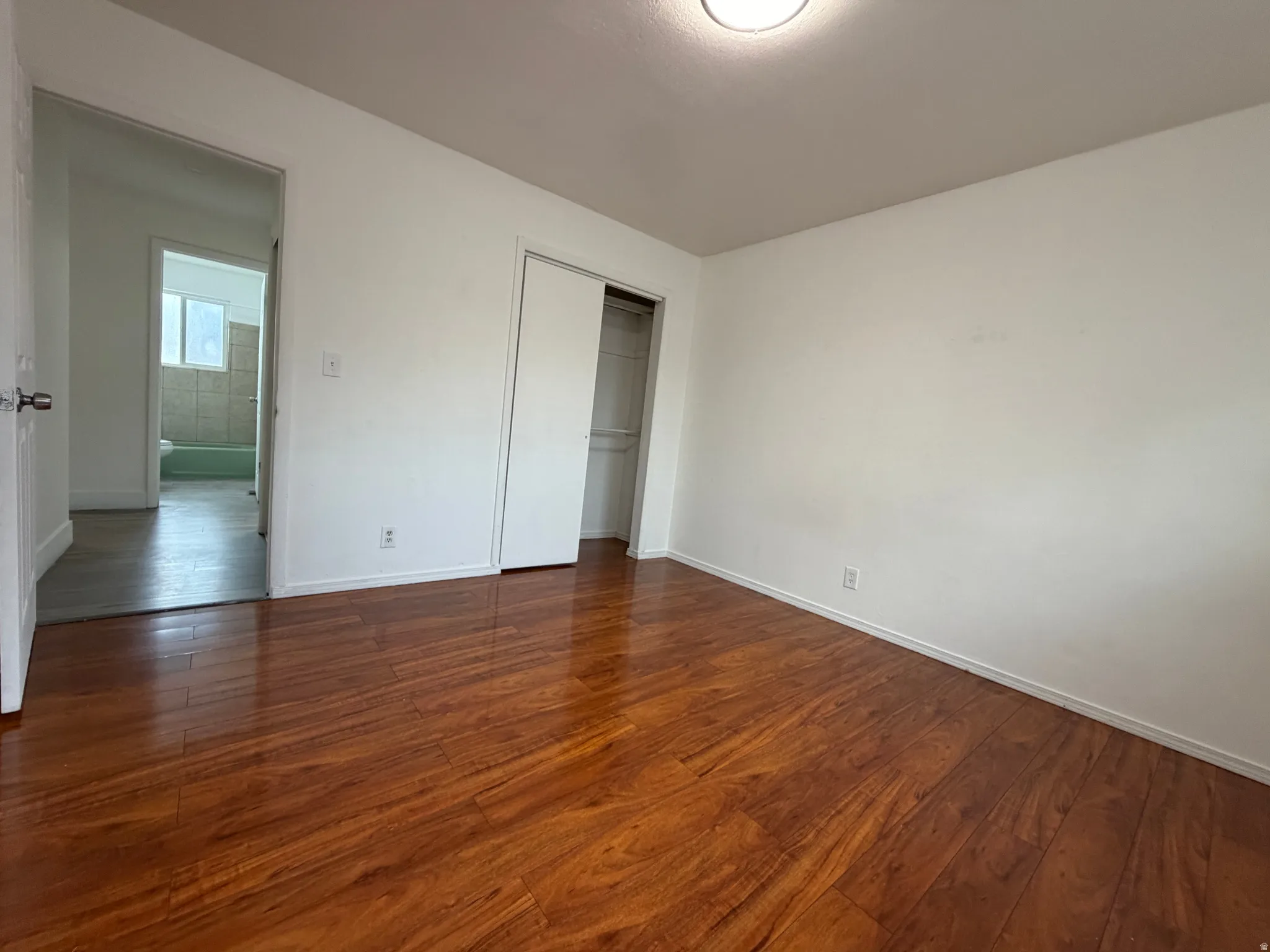 Wood-finish flooring throughout, white walls, and a recessed ceiling light