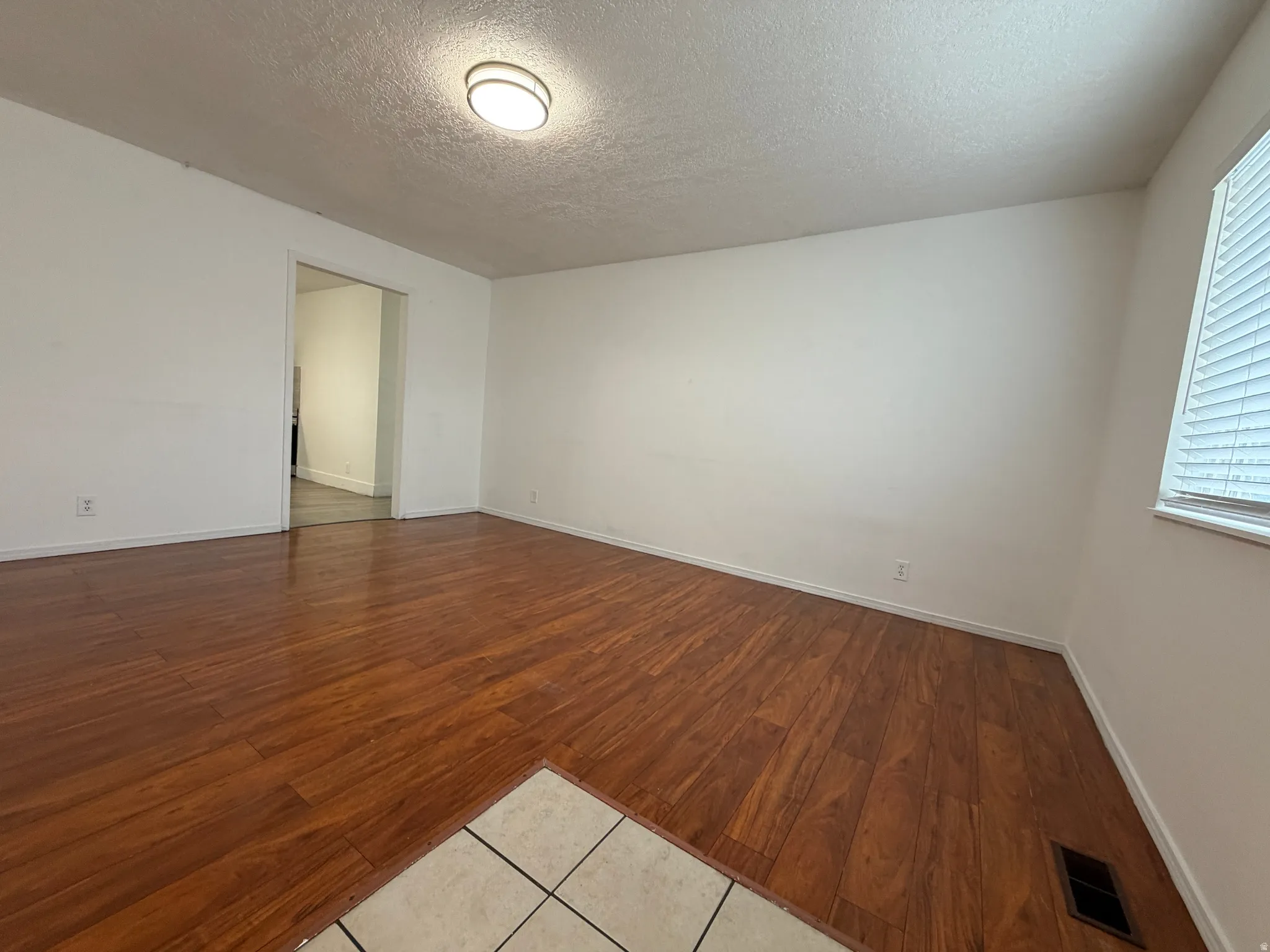 Wood-finish flooring throughout, bright white walls, and a recessed ceiling light fixture