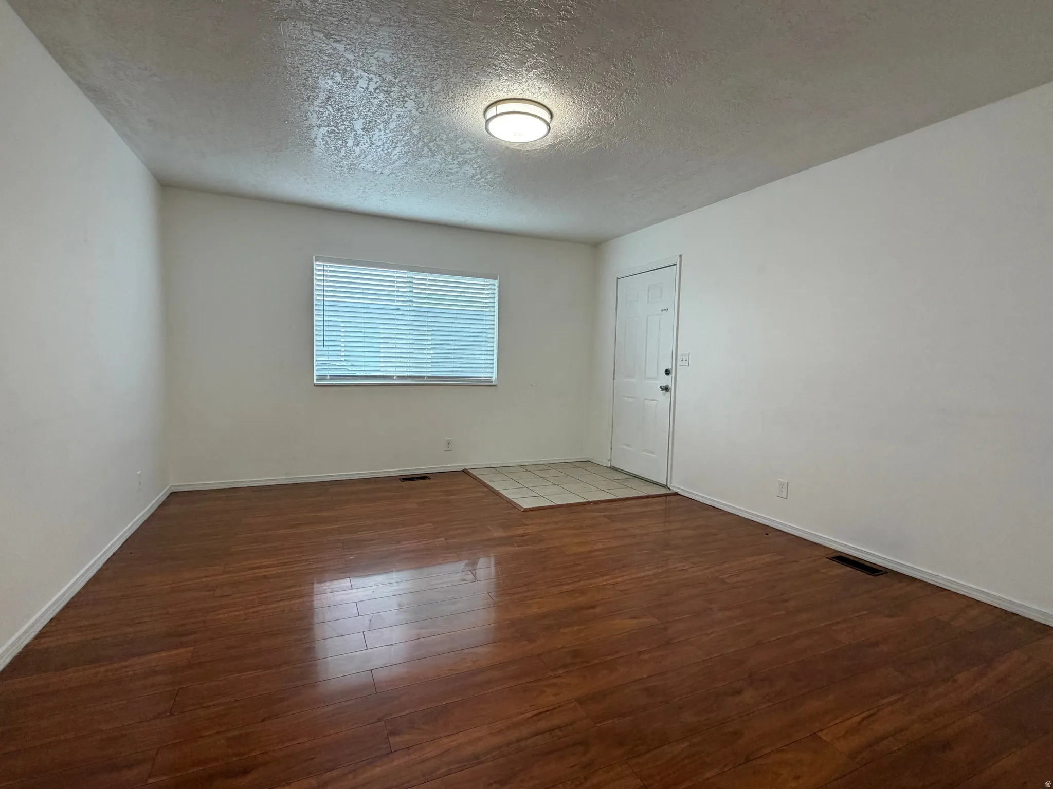 Wood-finish flooring, white walls, and a ceiling-mounted light fixture