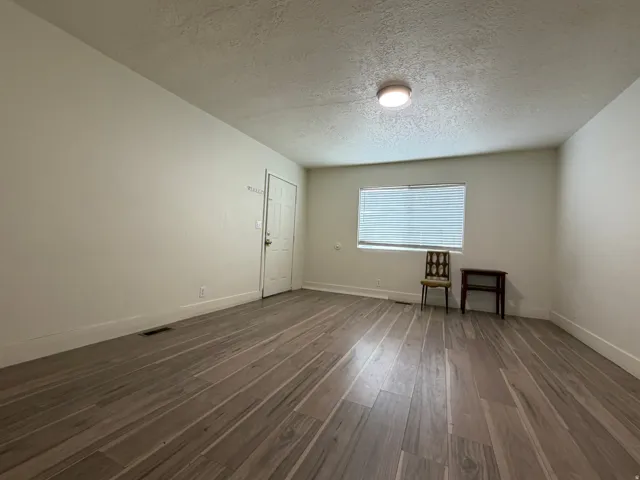 Wood-finish flooring, white walls, white trim, recessed lighting, and a single window with blinds