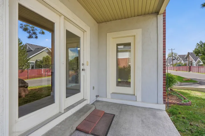 Covered porch entry featuring double glass-paneled doors, an additional single glass-paneled door, and a textured exterior finish