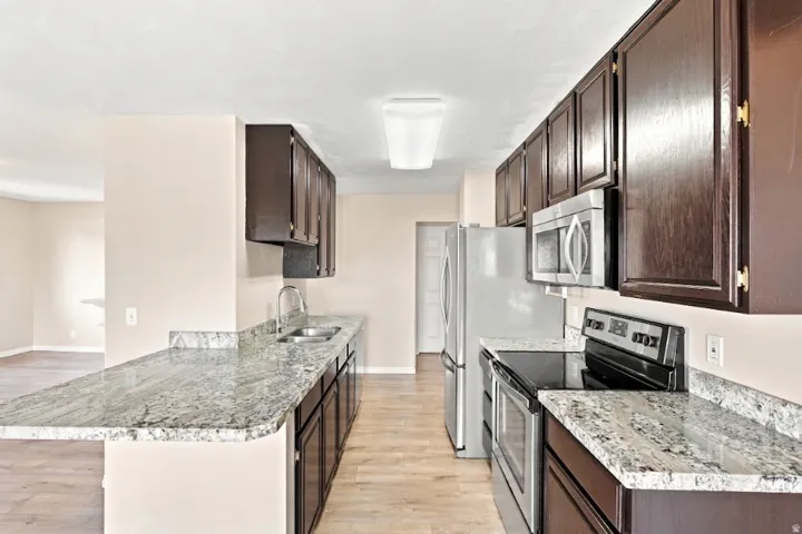 Kitchen featuring wood-finish flooring, dark wood cabinetry, and light-toned countertops