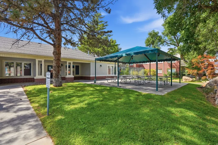 Expansive grounds featuring mature shade trees, manicured lawn, and a covered pergola structure with integrated seating area