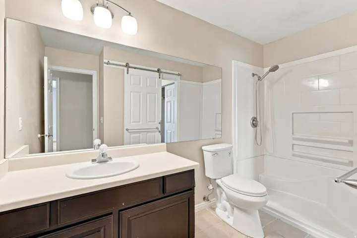 Dark wood-finish vanity with an integrated sink, polished chrome faucet, and expansive wall-mounted mirror