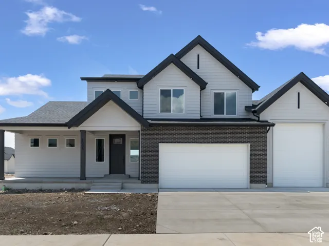 Contemporary exterior with light gray siding, dark brick accents, and a covered front porch