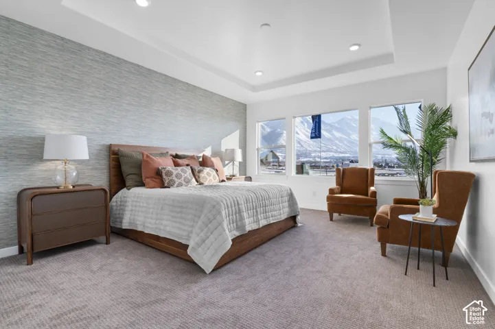 Recessed lighting, tray ceiling, textured accent wall, multiple windows, and carpeting