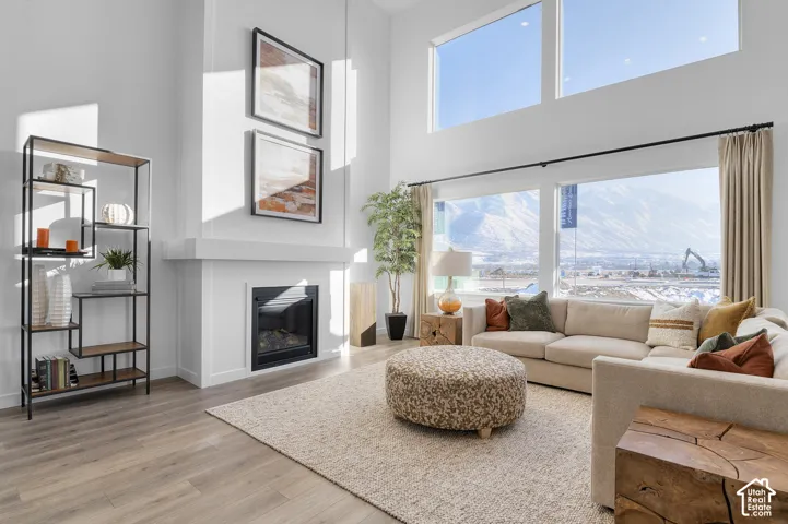 Spacious living area featuring high ceilings, large windows, a built-in fireplace, and wood-finish flooring