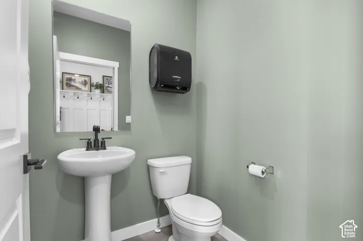 Pedestal sink with a black-finish faucet, rectangular wall-mounted mirror, and white toilet