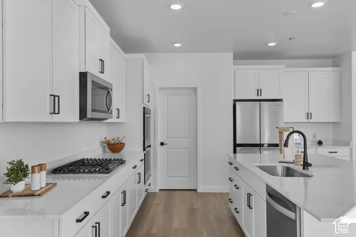 Modern kitchen featuring white cabinetry, stone countertops, stainless steel appliances, a gas range, and wood-finish flooring