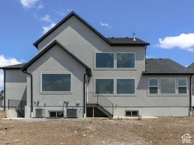 Contemporary stucco exterior with multiple large windows, dark shingle roof, and exterior staircase