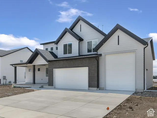 Modern two-story exterior with light gray siding, dark brick accents, and black trim