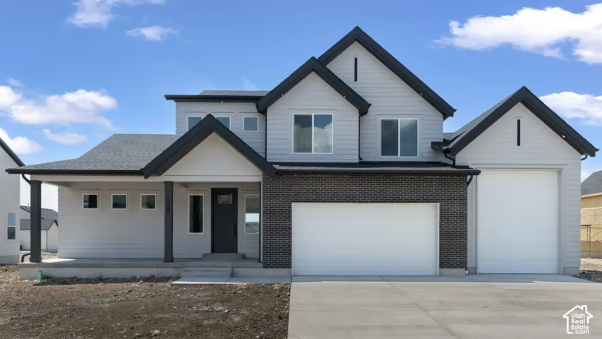 Contemporary exterior featuring light grey siding, a dark grey brick accent, and a covered porch entry