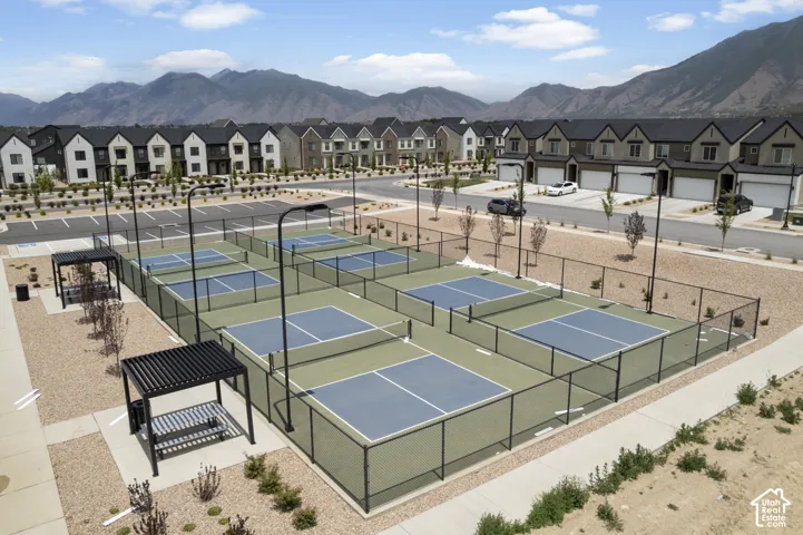 Multiple pickleball courts with perimeter fencing, permanent lighting fixtures, and dedicated shaded seating areas