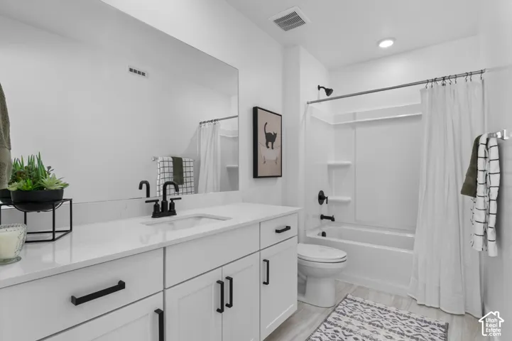 Modern bathroom featuring a white vanity with black hardware, an integrated sink with a matte black faucet, a large frameless mirror, and a white tub/shower combination