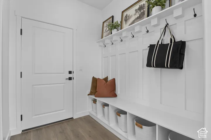 Entryway featuring wood-finish flooring, a white paneled door with matte black hardware, and a built-in bench with storage cubbies