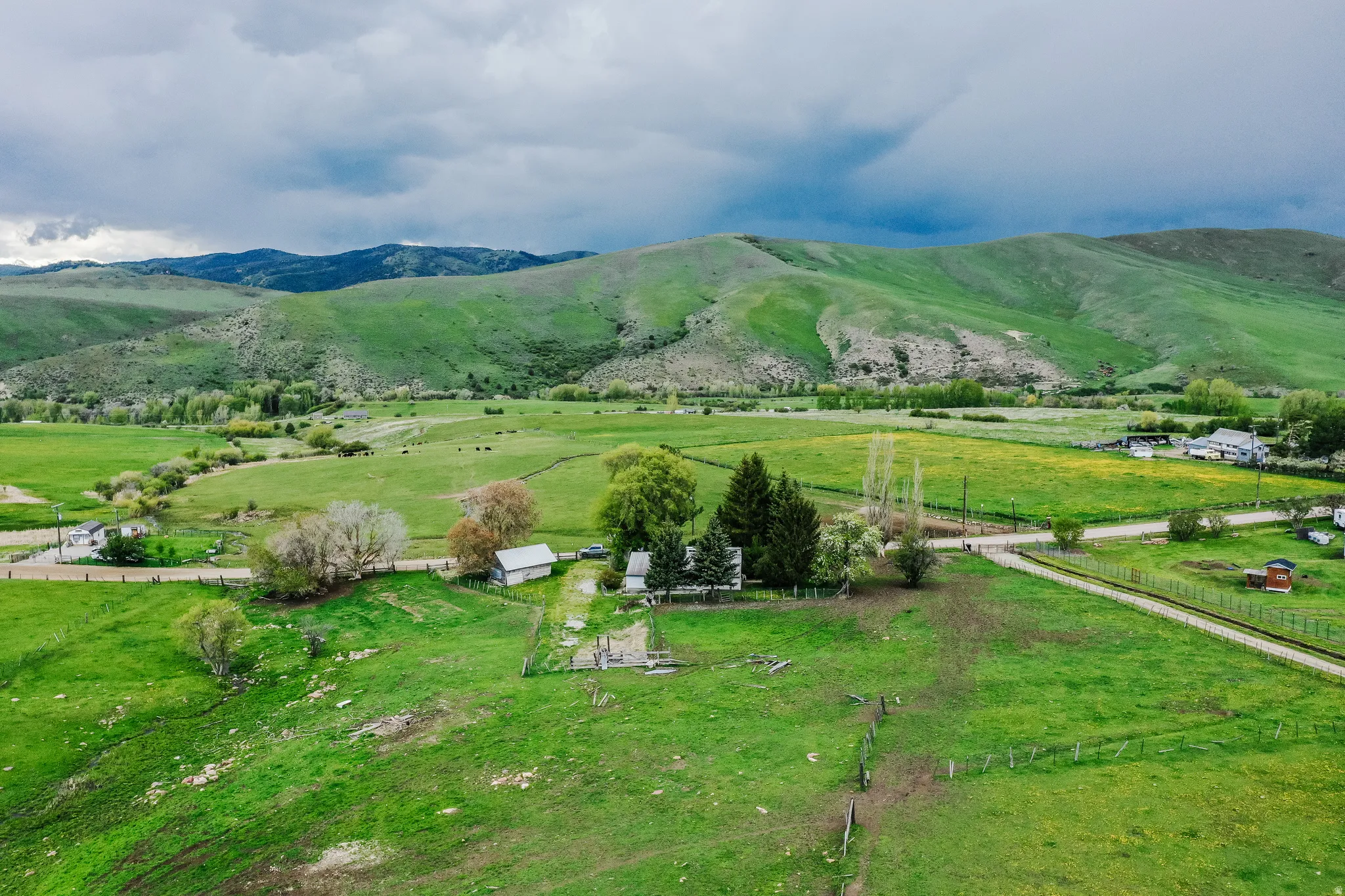 Expansive green fields with distant rolling hills and a residential structure