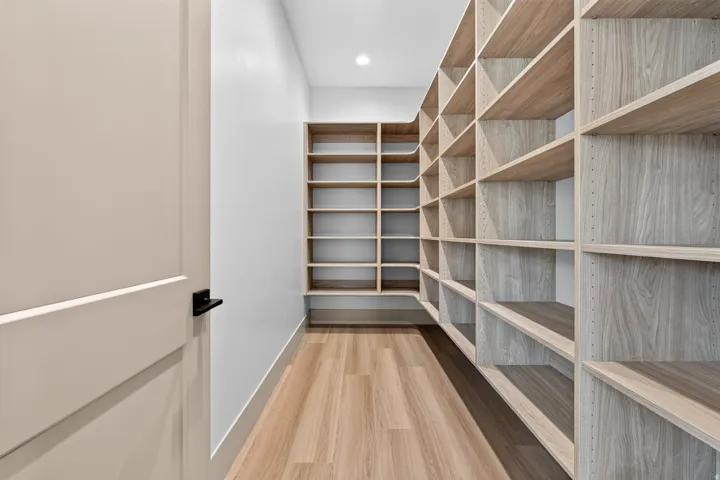 Expansive custom shelving with light wood-finish, recessed lighting, and wood-finish flooring