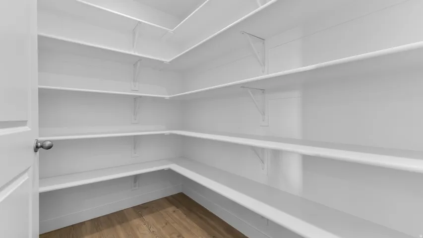 Walk-in pantry with extensive built-in shelving, durable wood-finish flooring, and a neutral color palette