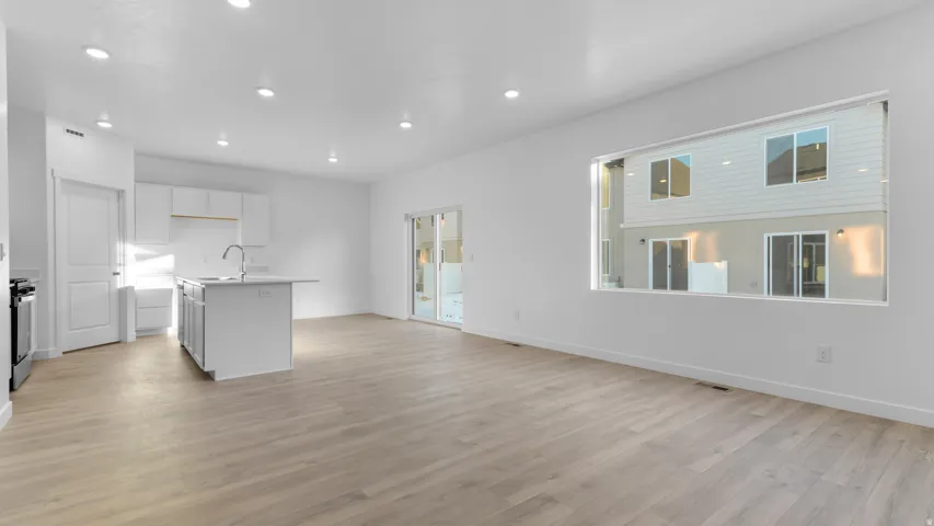Open-concept living space featuring wood-finish flooring, recessed lighting, and a kitchen island with an undermount sink