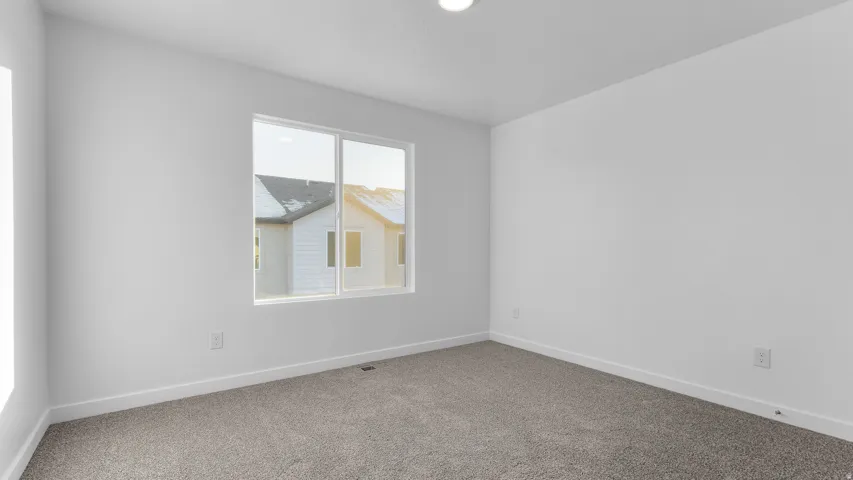 Neutral-toned carpeting paired with white walls, a single window, and recessed ceiling lighting