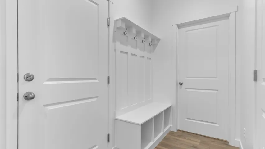 Built-in storage bench with cubbies, white paneling, and hooks