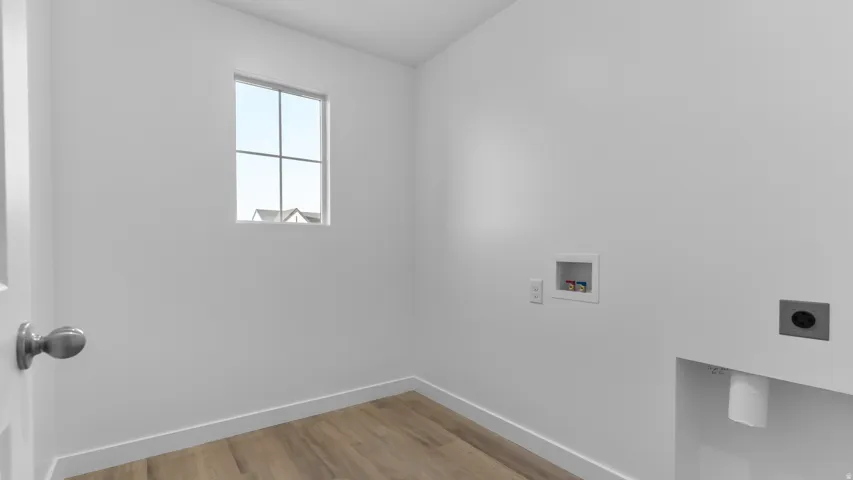 Laundry area featuring wood-finish flooring, a window, and utility connections