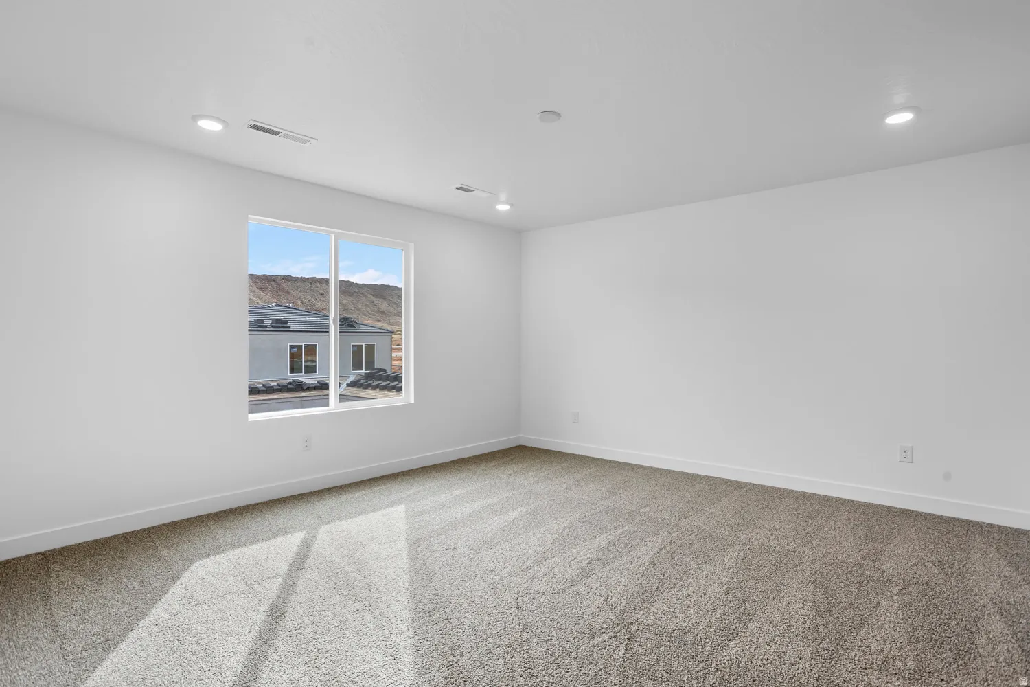 Expansive room with neutral carpet flooring and white walls