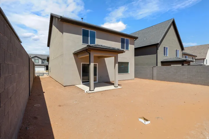 Spacious backyard with perimeter block walls, covered patio, and stucco exterior