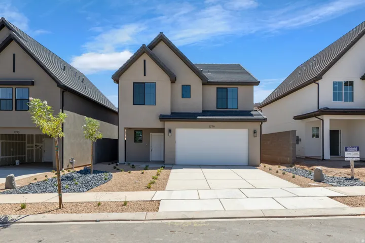 Stucco exterior with a multi-gabled roofline, integrated garage, and a concrete driveway