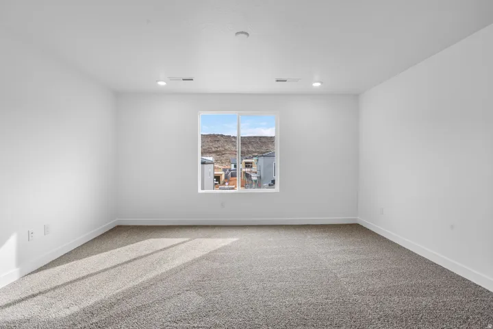 Recessed lighting, large window, neutral carpet, white walls, and mountain scenery