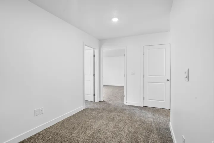 Plush carpet flooring, white painted walls, recessed ceiling light, and white interior doors
