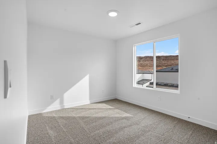 Neutral wall color, carpet flooring, recessed lighting, and a large window