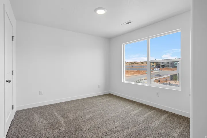 Recessed ceiling light, white painted walls, large window, gray carpet, and white trim
