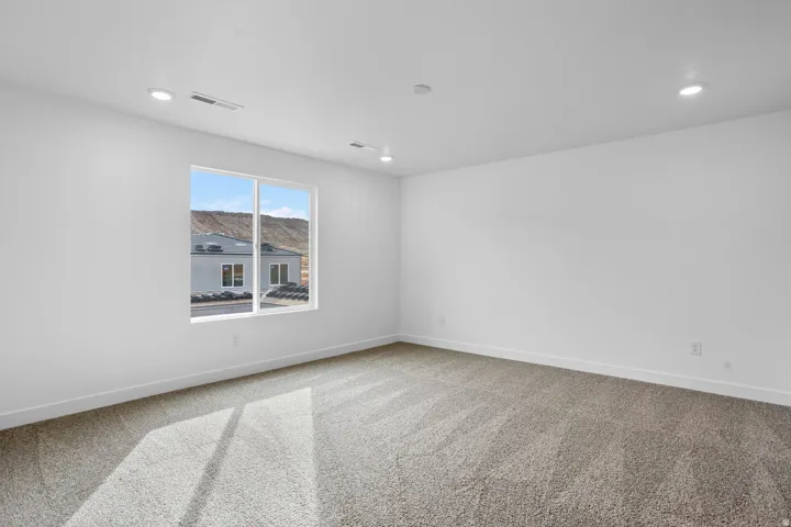 Expansive room with neutral carpet flooring and white walls