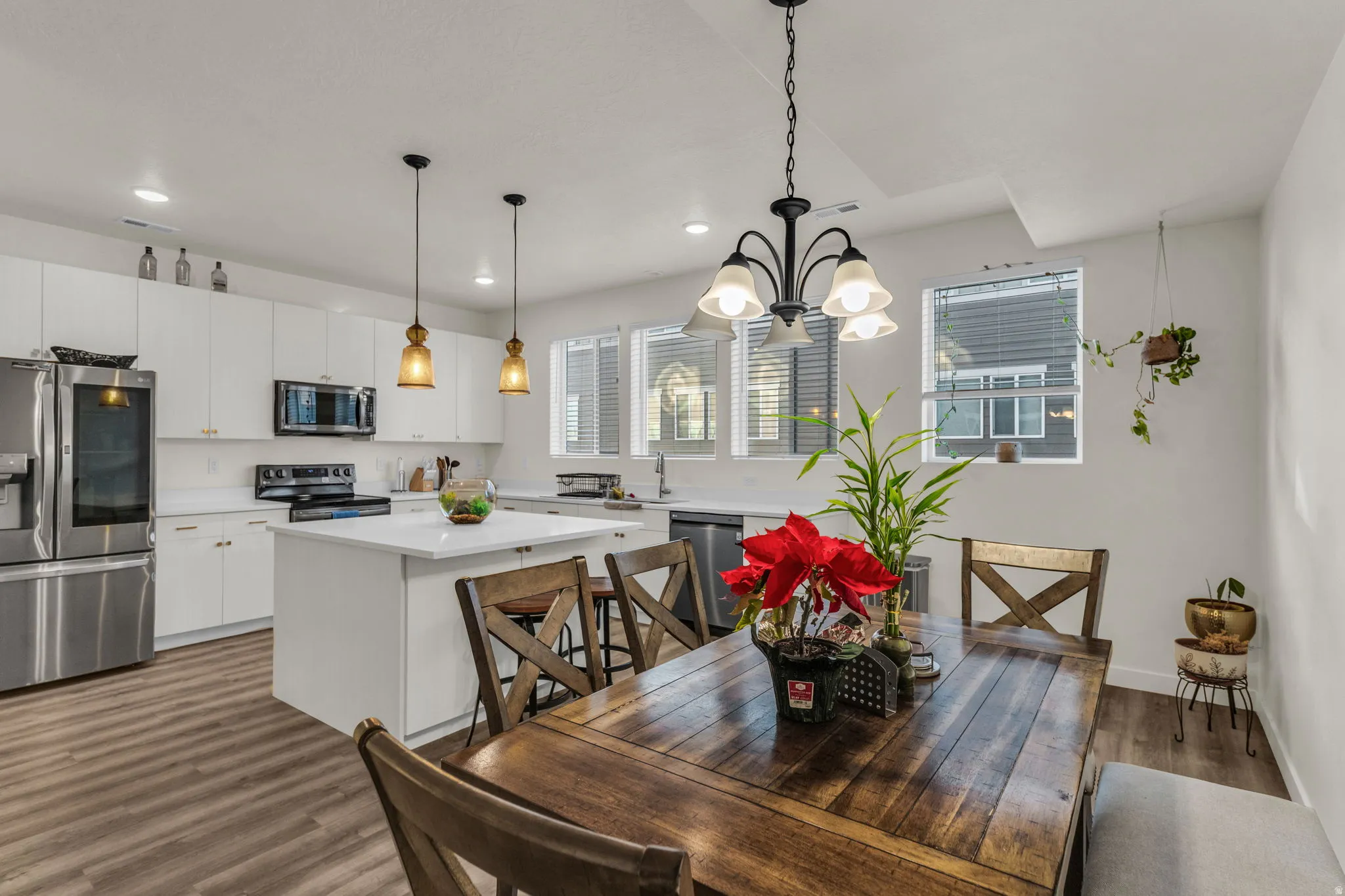 Open-concept kitchen and dining area featuring white cabinetry, stainless steel appliances, a center island, and wood-finish flooring