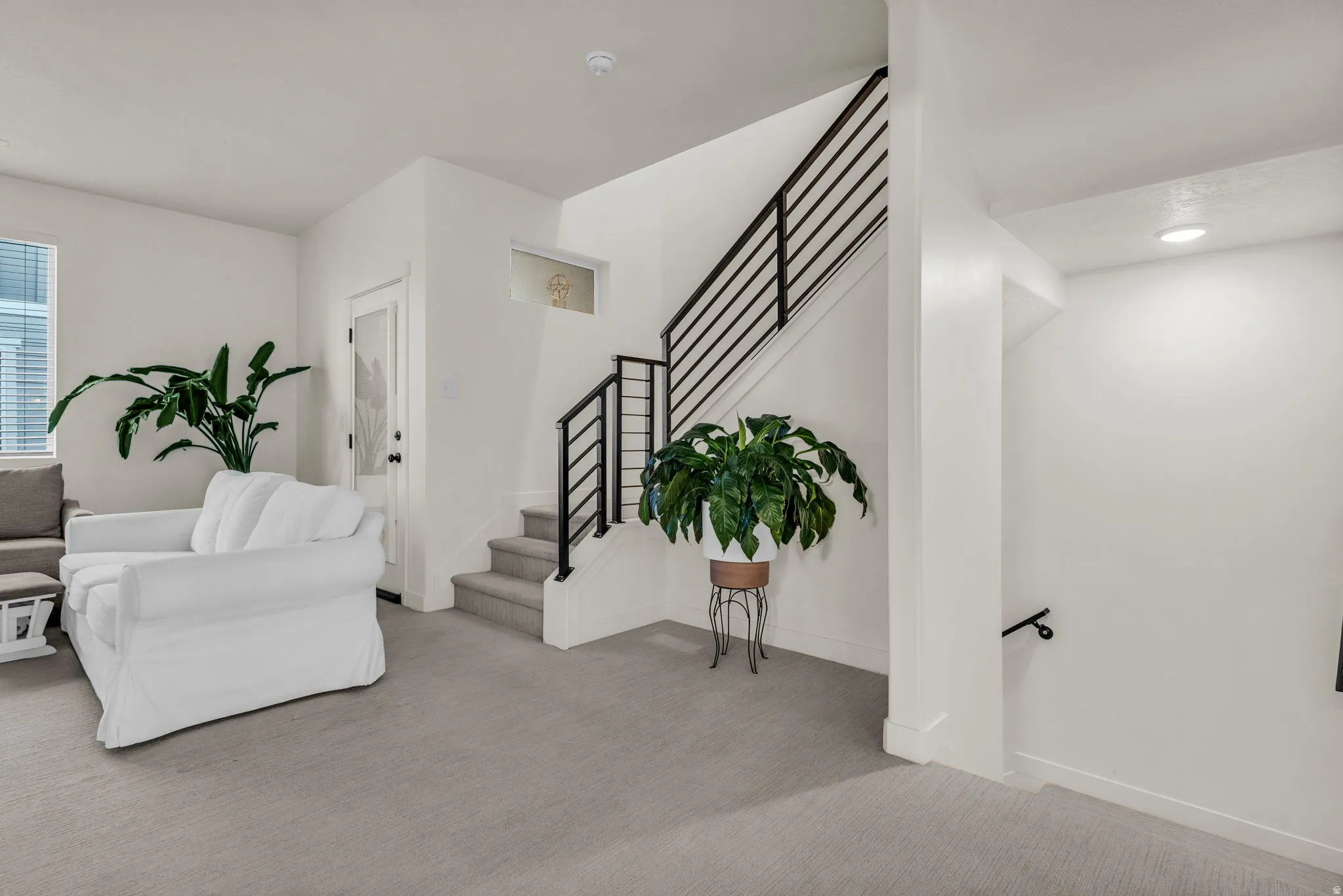 Carpeted flooring throughout, staircase with modern black railings, recessed ceiling lighting, and a transom window