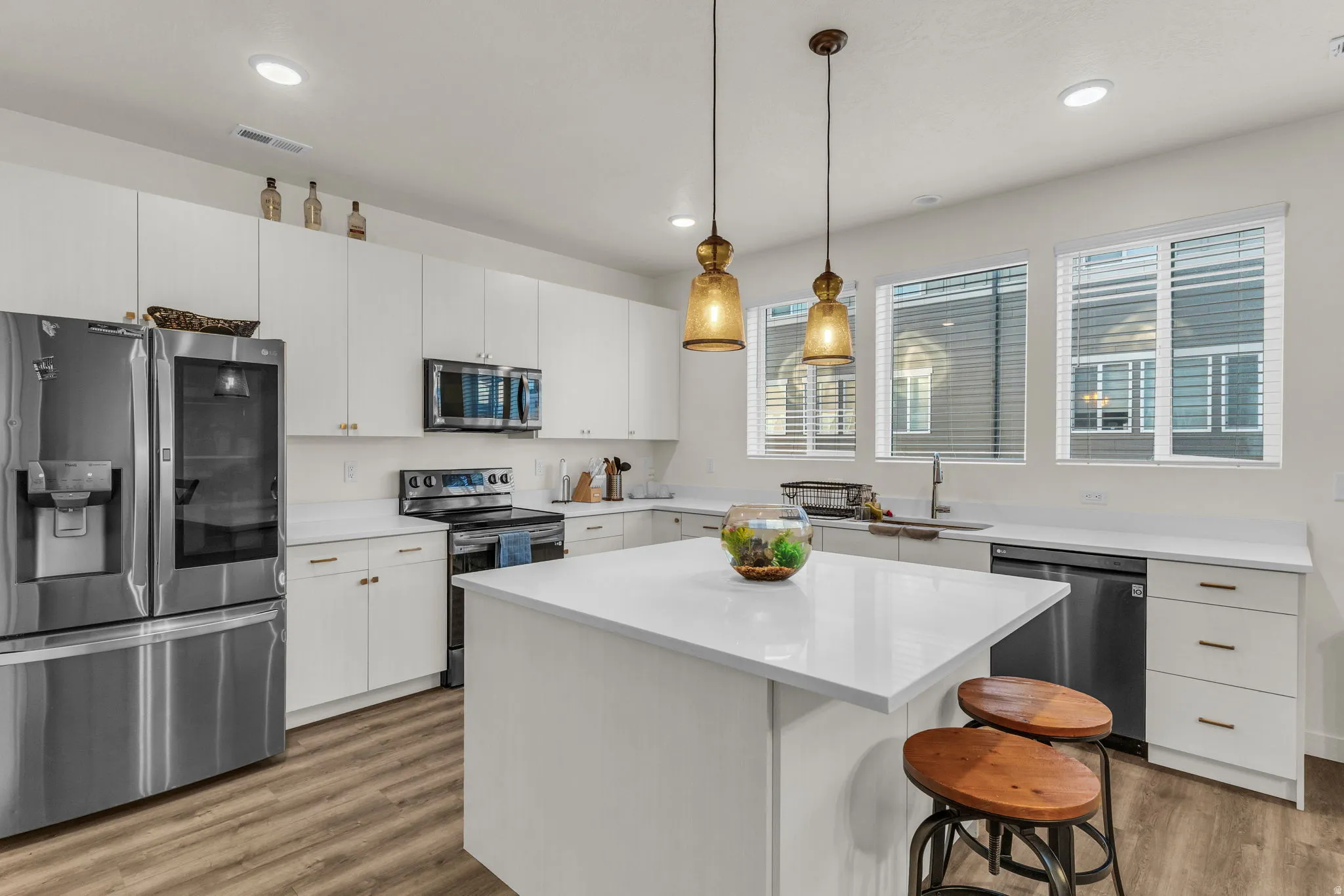 Kitchen featuring stainless steel appliances, white cabinetry, a central island with countertop, recessed lighting, and wood-finish flooring