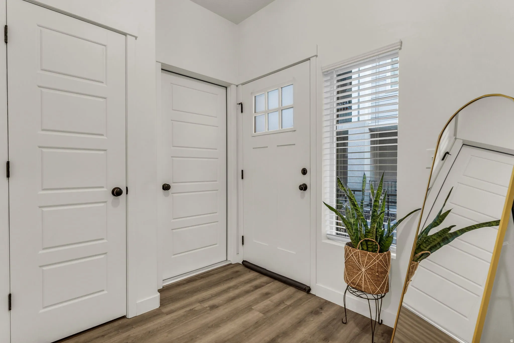 Wood-finish flooring, white panel doors, and a front entry door with a frosted glass insert